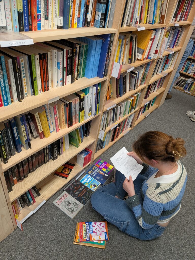 A university student sitting on the floor selecting books